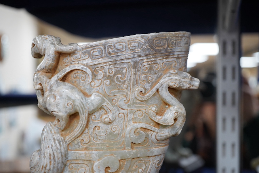 A large Chinese archaistic pale celadon and calcified jade rhyton, on a hardwood stand, 17.5cm high. Condition - fair to good.